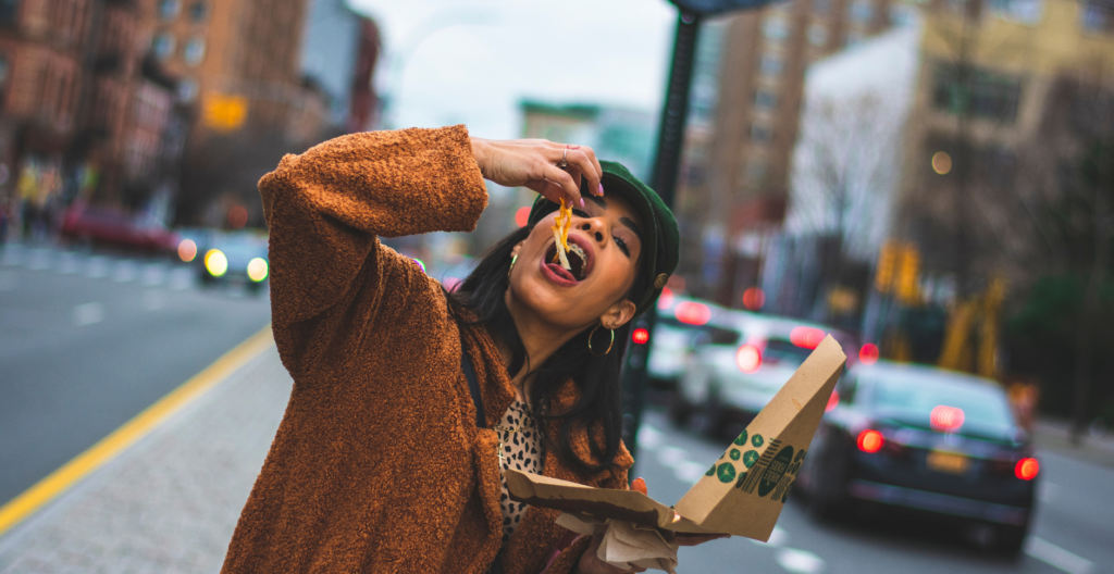 Woman eating pizza from the box outdoors in the city