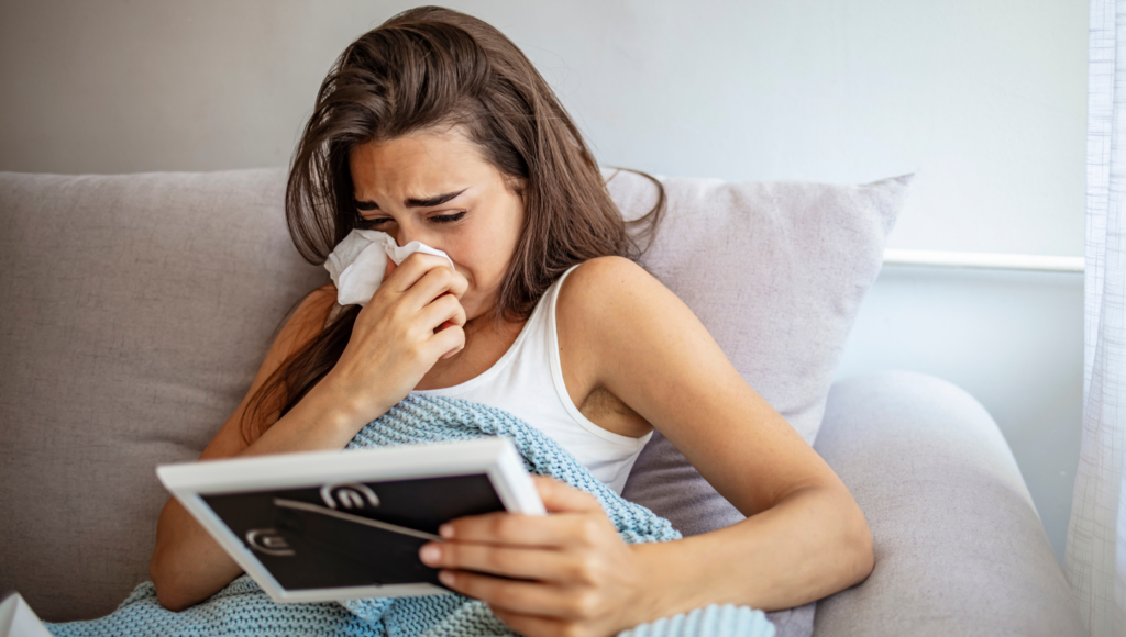 Young woman crying in bed while looking at a picture frame