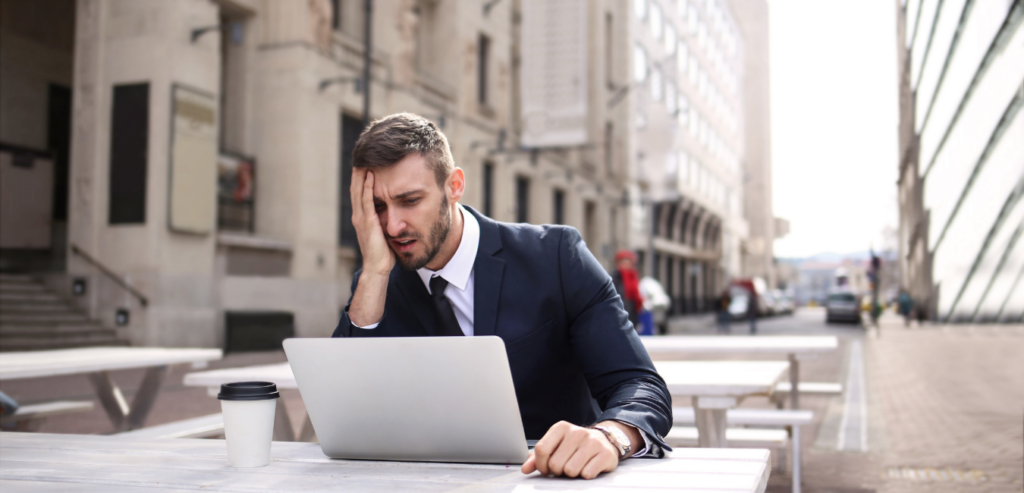 Man in business suit looking stressed while working on laptop