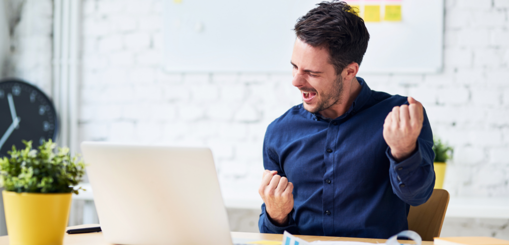 Young man in office victoriously pumping fist in the air﻿