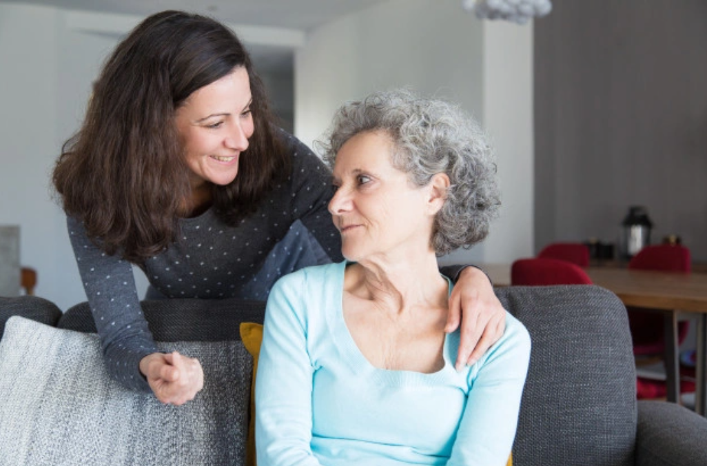 Young woman cheering up elderly loved one