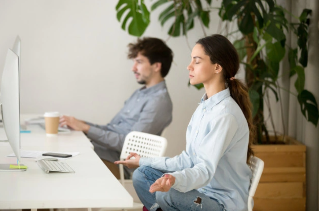 Woman meditating while siting at office desk﻿﻿